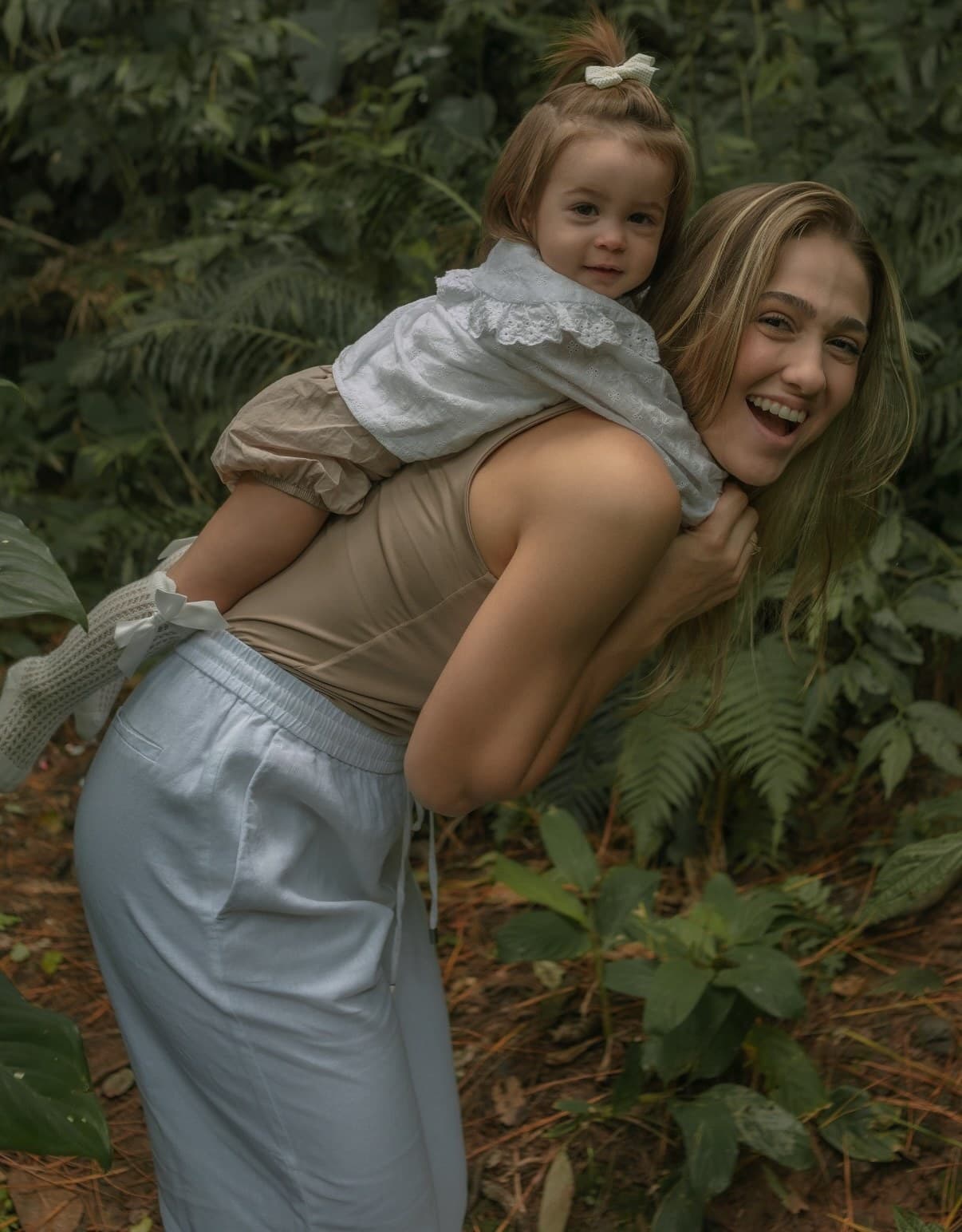 Rúbia Tretto carregando a filha nas costas, as duas sorrindo